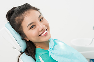 Woman in need chair smiling after emergency dentistry