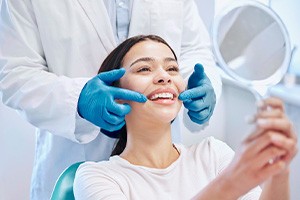 Happy dental patient looking at her smile in mirror