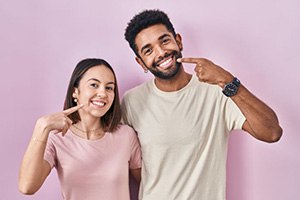 Happy young couple pointing at their teeth