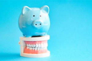 Blue piggy bank sitting on top of dental model