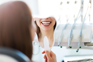 Woman looking in mirror after smile makeover