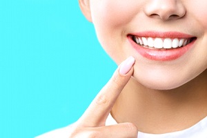 Woman pointing at her beautiful teeth after cosmetic bonding