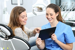Happy patient and dental team member looking at tablet together