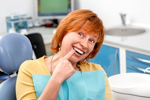 Delighted female dental patient pointing at her dentures