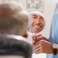 Man looking at smile in mirror after replacing knocked out tooth