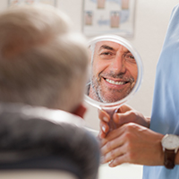 Man looking at smile in mirror after replacing knocked out tooth
