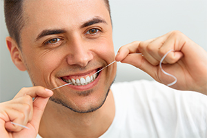 Man flossing teeth to prevent dental emergencies