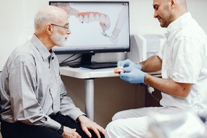 Senior man talking to dentist, learning about implant dentures