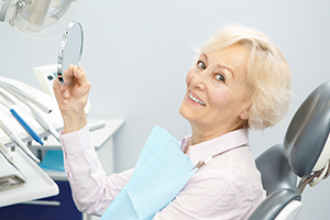 Woman looking at smile after dental implant tooth replacement