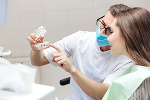 Dentist showing patient a dental implant restoration model