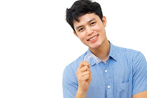 Happy young man holding his aligners for Invisalign in Needham 