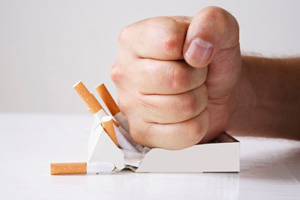 Person’s fist smashing a pack of cigarettes