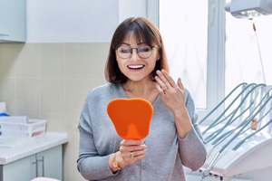 Dental patient admiring her new smile in the mirror