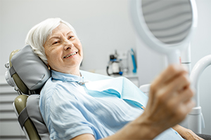 Woman checking new dentures in mirror