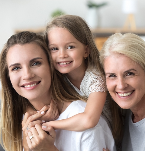 Three generations of women smiling after preventive dentistry visit