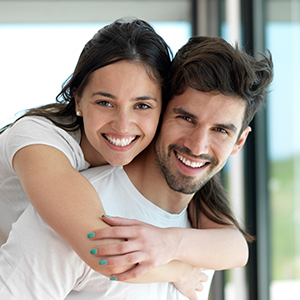 Man and woman smiling after receiving treatment using advanced dental services and technology