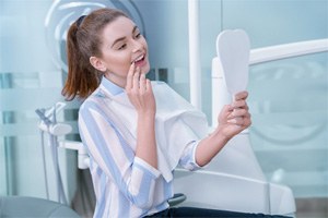 Woman using mirror to admire the results of her cosmetic treatment