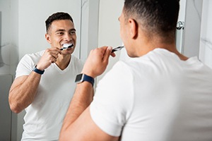 Man brushing his teeth to maintain results of his whitening treatment