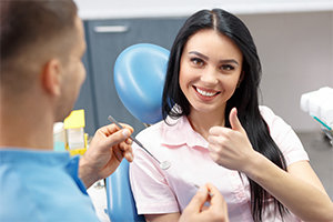 Woman smiling giving thumbs up after wisdom tooth extractions