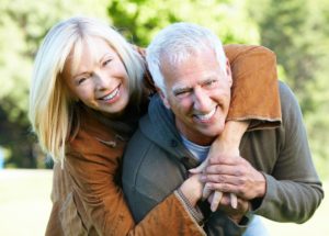 Senior couple laughing and smiling after adjusting to implant dentures