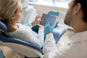 Dentist and patient looking at tablet, conversing about treatment options