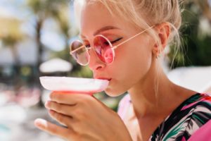 Woman sitting outside, sipping an alcoholic beverage