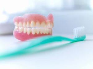 Set of dentures next to toothbrush