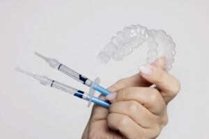 Hand holding components of teeth whitening kit 